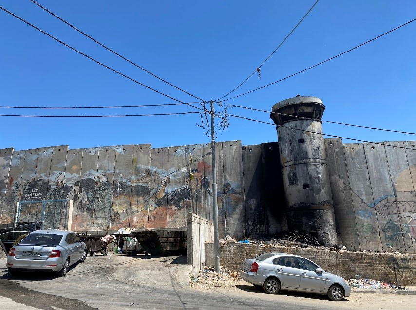 Caption: The partition wall next to Aida camp has seven watch towers. The watch tower pictured has been destroyed, but the surroundings still bear the scars of Israeli surveillance and attacks. The wall of the building opposite this tower is riddled with marks from bullets.